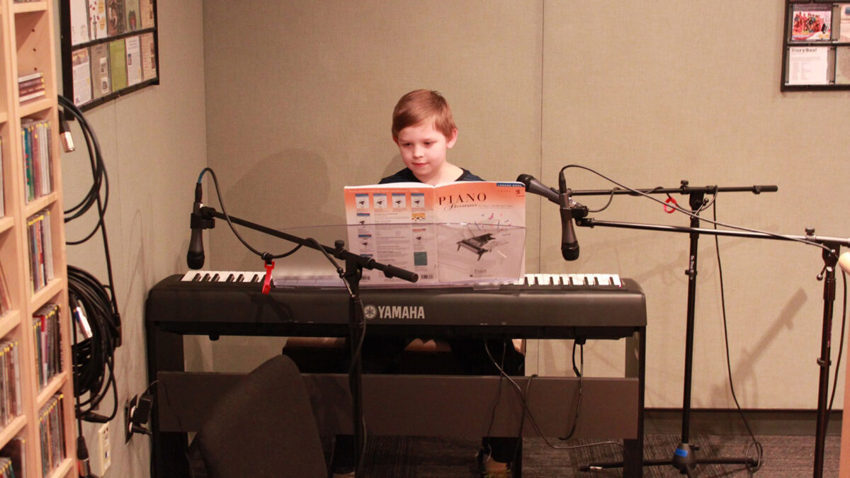 A youth playing a piano keyboard in a radio studio