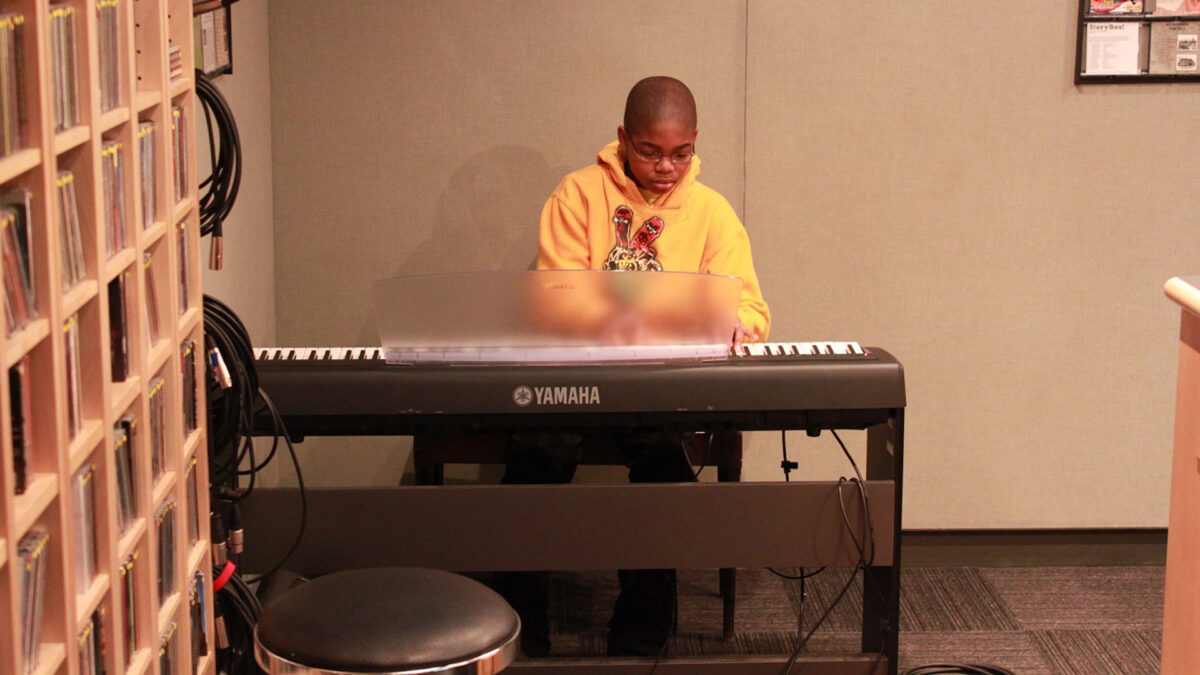 A youth playing a piano keyboard in a radio studio