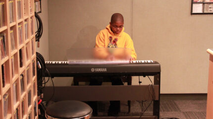 A youth playing a piano keyboard in a radio studio