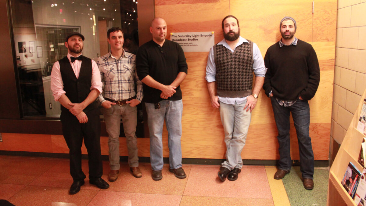 Five adults posing in front of a radio studio
