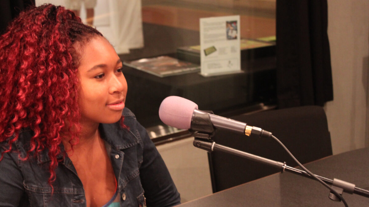 A teen speaking into a microphone in a radio studio
