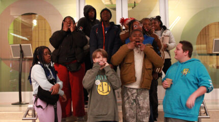 Eleven youth making silly faces at the camera while standing on a staircase