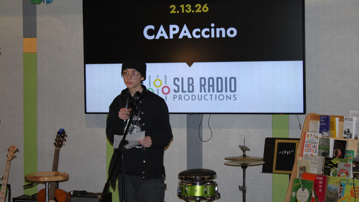 A teen reading a piece of paper into a microphone