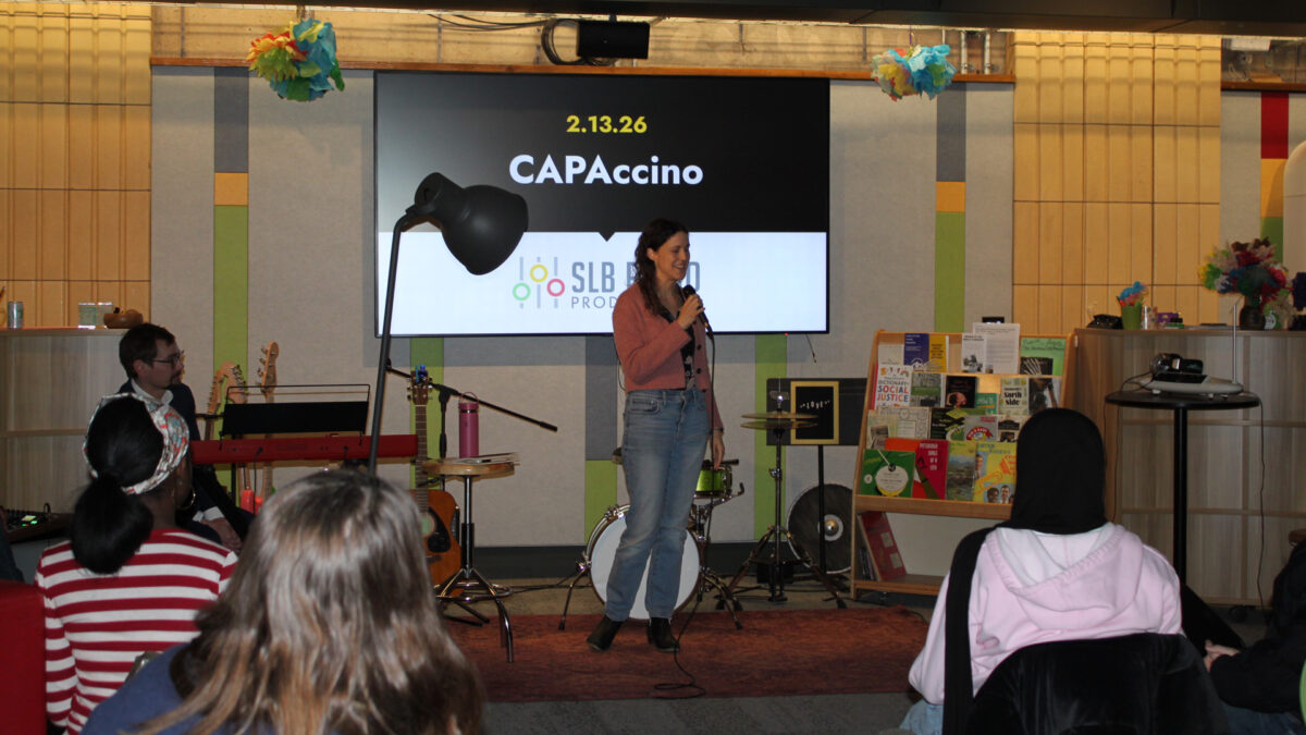 Three teens and an adult listening to a teen speaking into a microphone