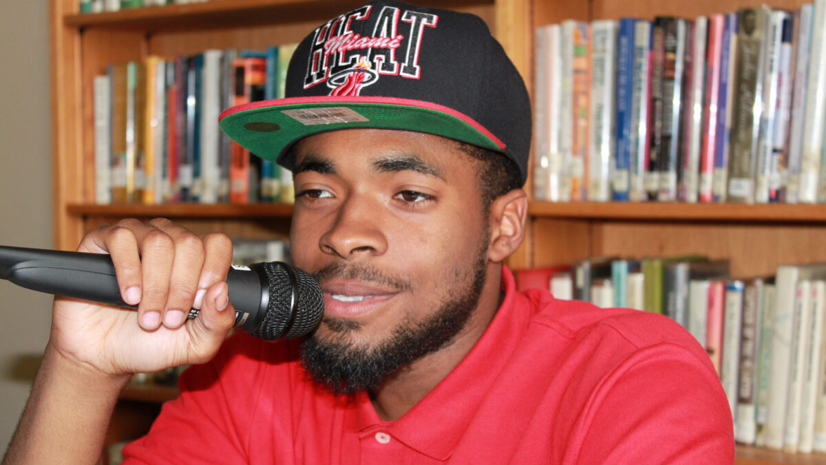 A teen holding and speaking into a microphone in a library