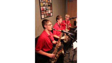 Two teens playing alto saxophone and a teen playing tenor saxophone in a radio studio