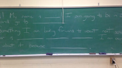 Text written on a green chalkboard in a classroom