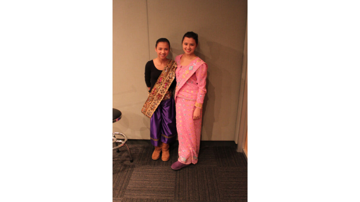 Two teens smiling and standing in profile in a radio studio