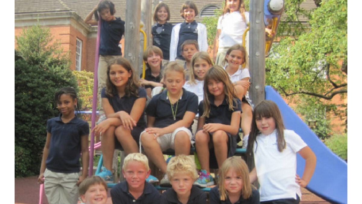 Seventeen youth sitting on a playground structure smiling at the camera