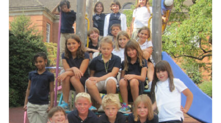 Seventeen youth sitting on a playground structure smiling at the camera