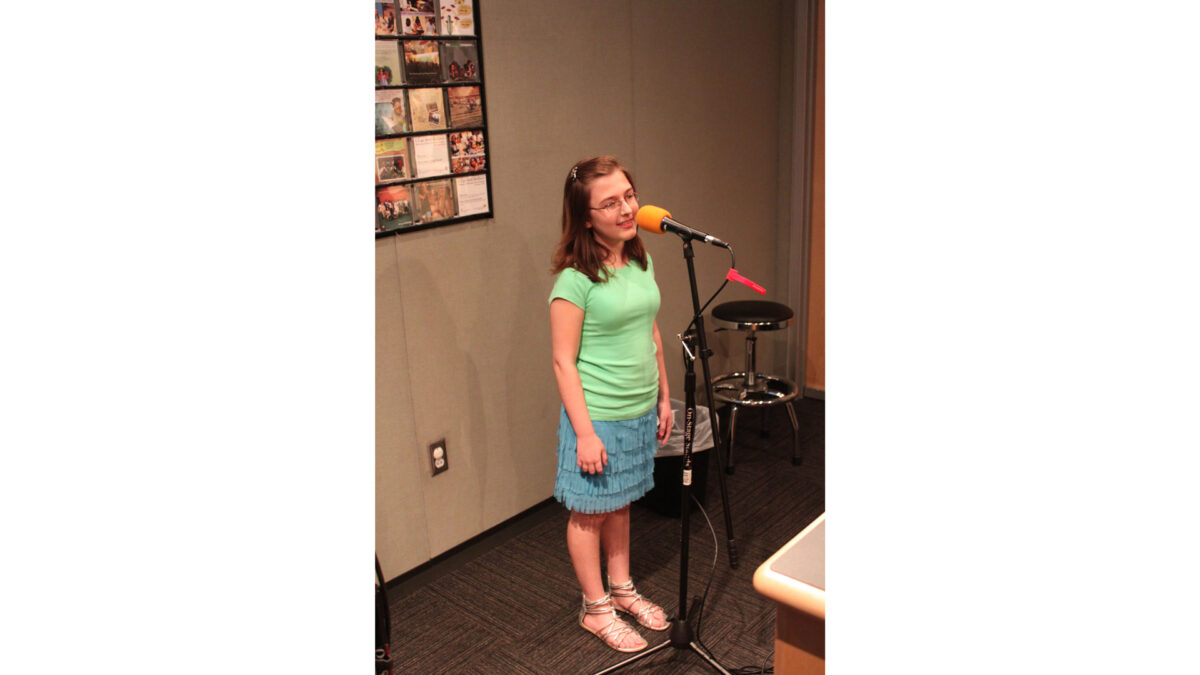 A youth standing behind a microphone in a radio studio