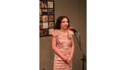 A youth singing into a microphone in a radio studio