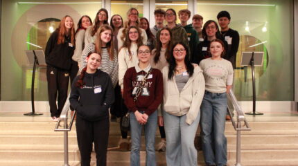 Eighteen teens smiling and standing on a set of stairs