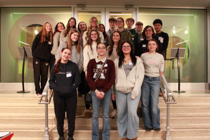 Eighteen teens smiling and standing on a set of stairs