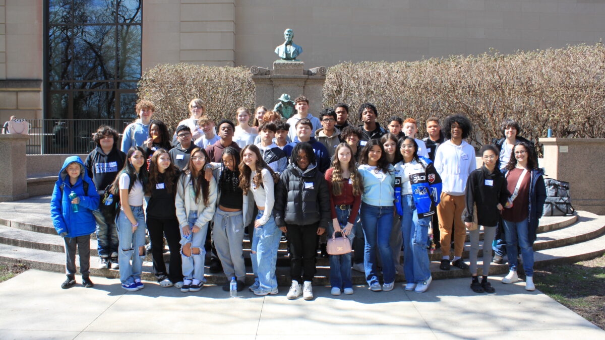 Thirty-six teens standing in front of a statue smiling at the camera