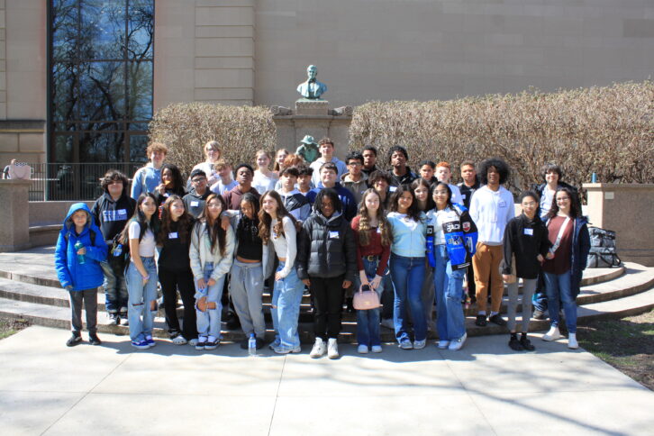 Thirty-six teens standing in front of a statue smiling at the camera