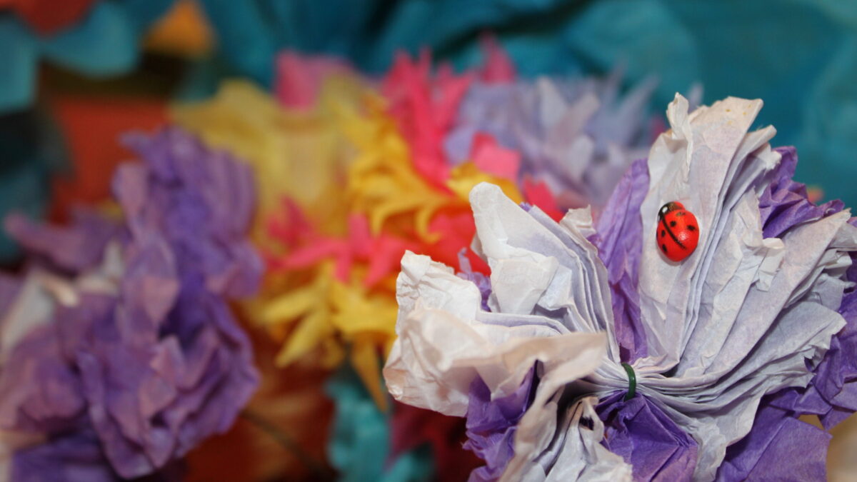 Three paper flowers, one with a handmade ladybug on it
