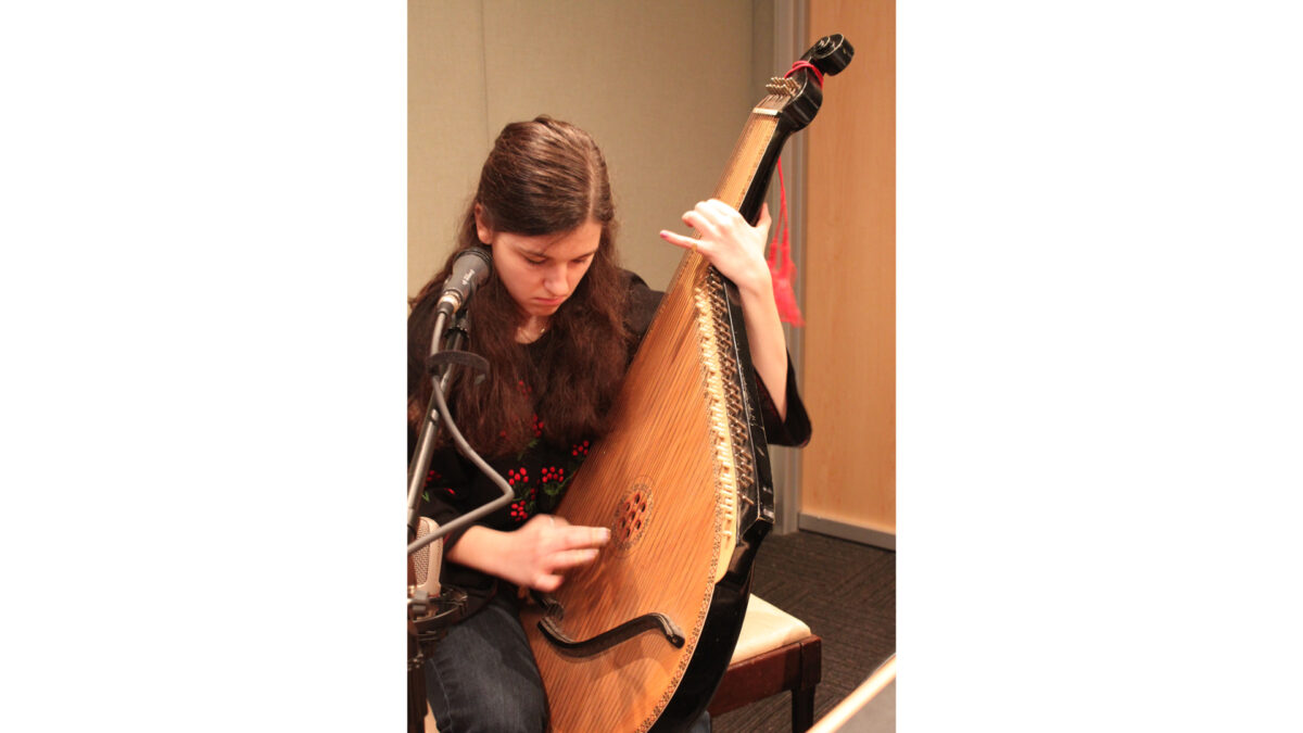 A teen playing a bandura in a radio studio