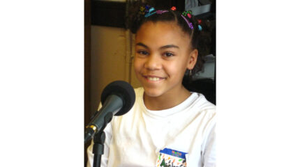 A youth smiling while sitting behind a microphone