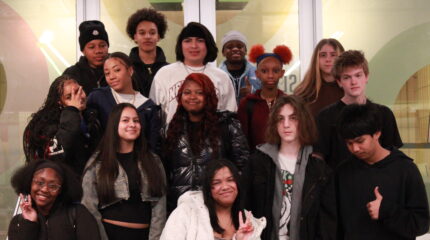 Fifteen teens smiling and posing on a staircase