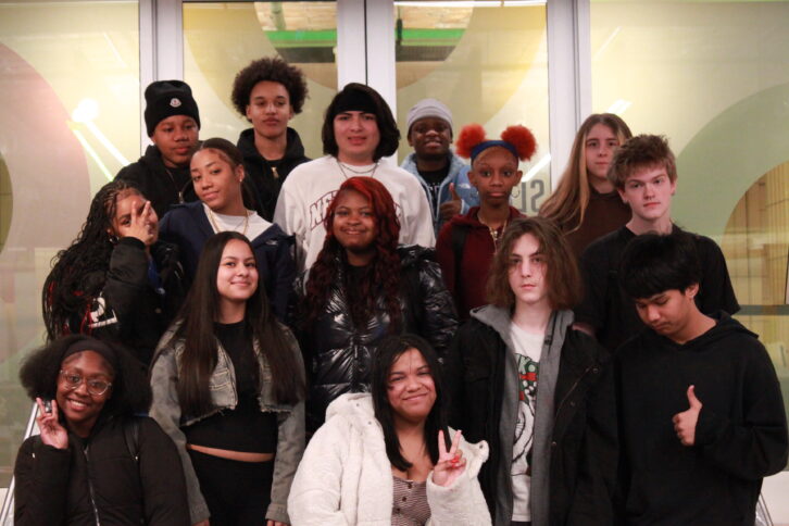 Fifteen teens smiling and posing on a staircase