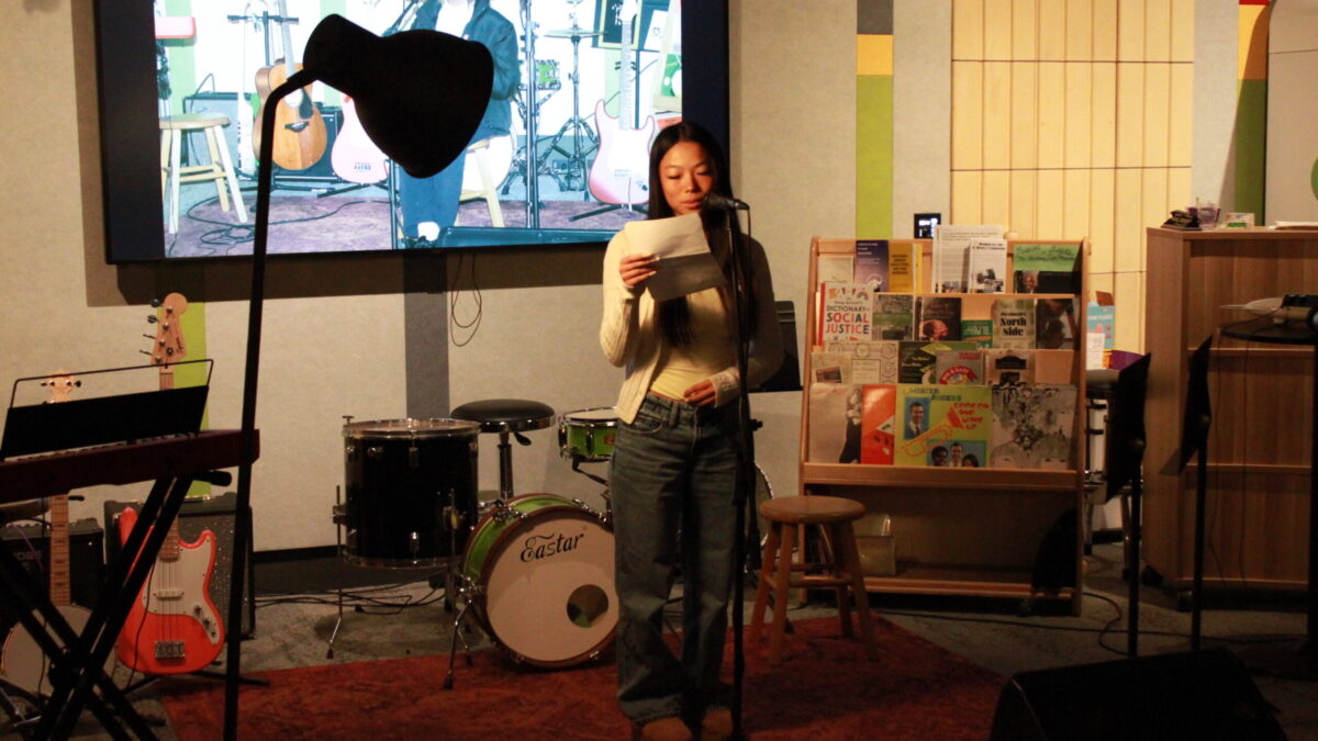 A teen reading from a piece of paper into a microphone