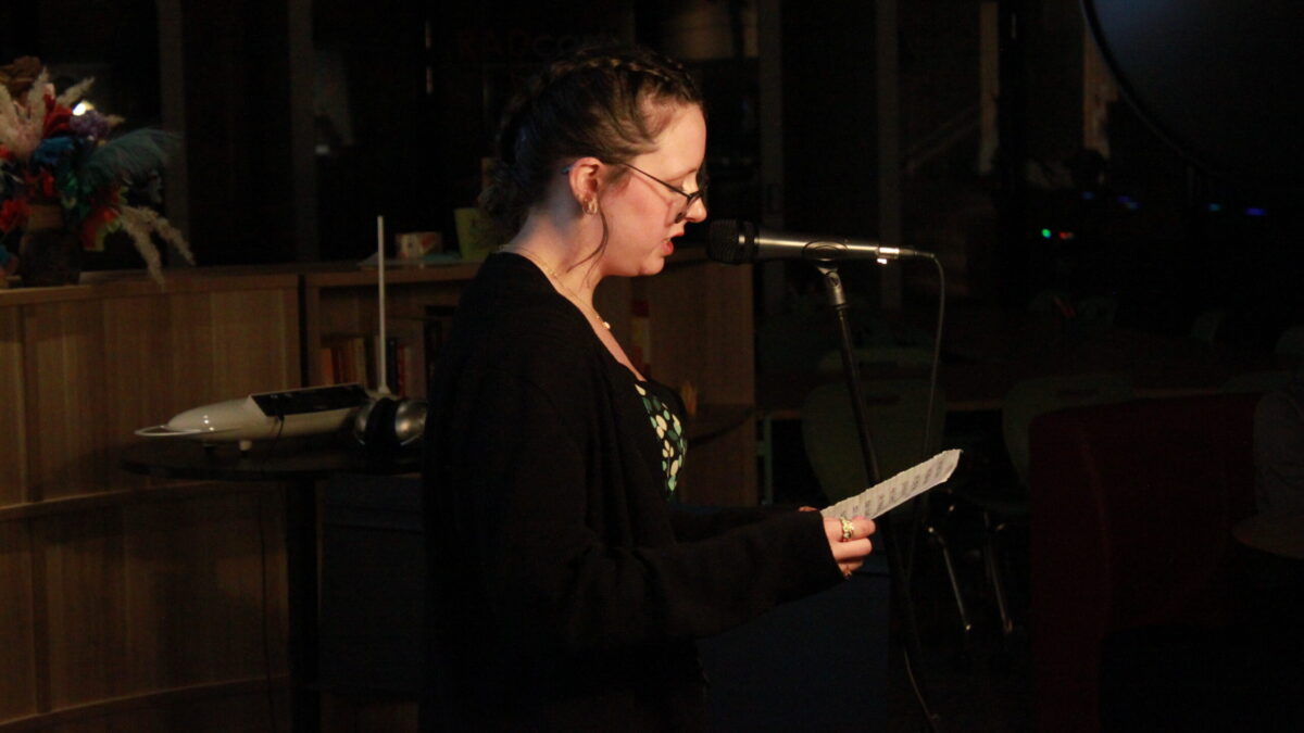 A teen reading from a piece of paper into a microphone