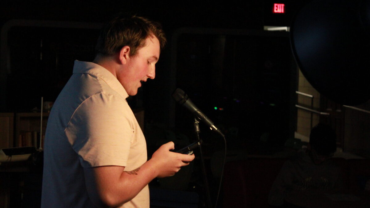 A teen reading from their smartphone into a microphone