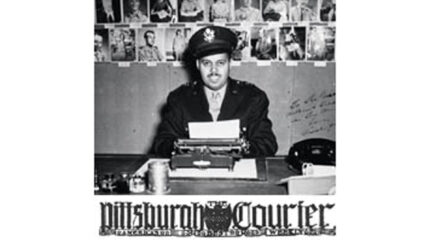 A black and white image of an adult sitting behind a typewriter and in front of multiple photographs
