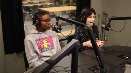 Two teens speaking into microphones in a radio studio