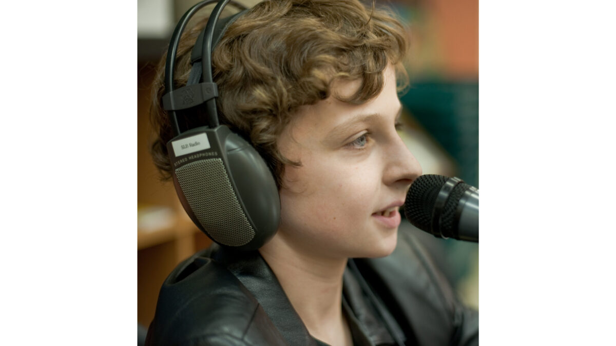 A youth wearing headphones speaking into a microphone