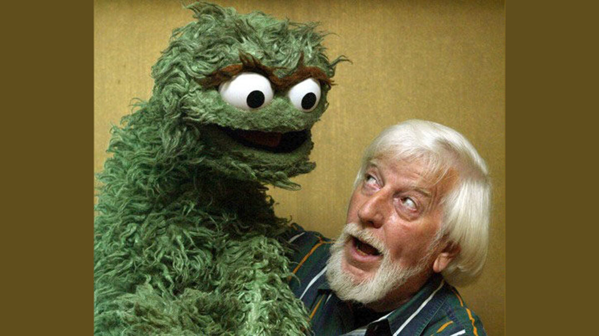 An adult holding a large puppet and smiling up at it