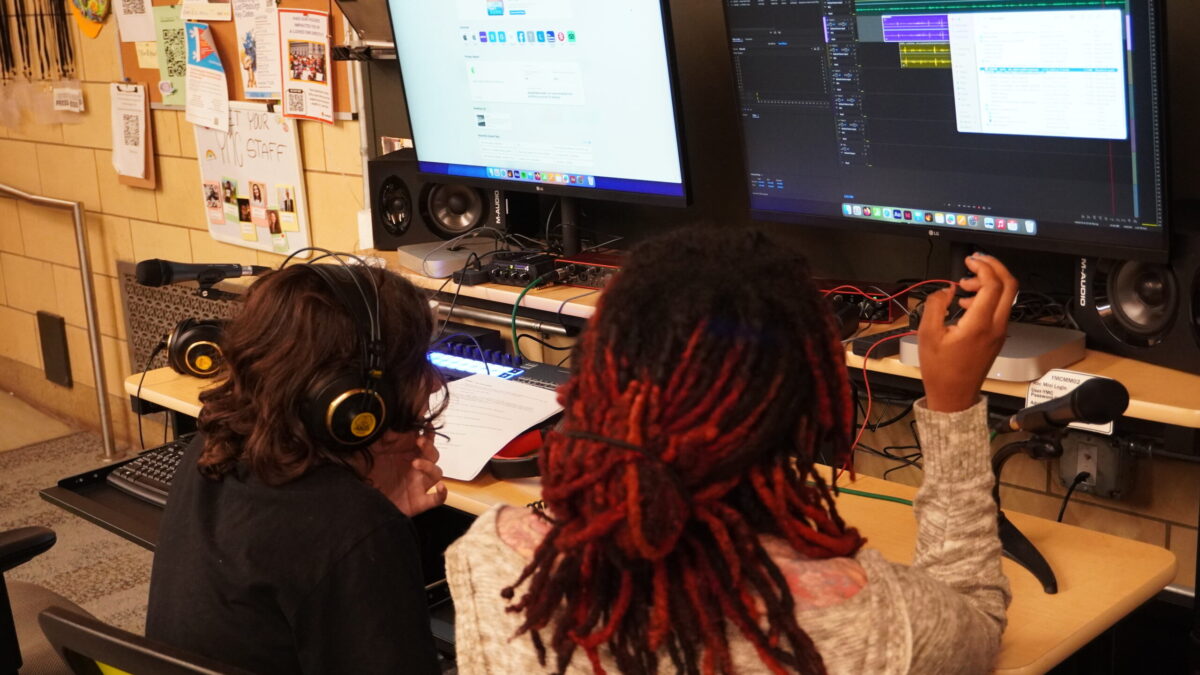 A teen and adult reviewing audio clips on a computer monitor.