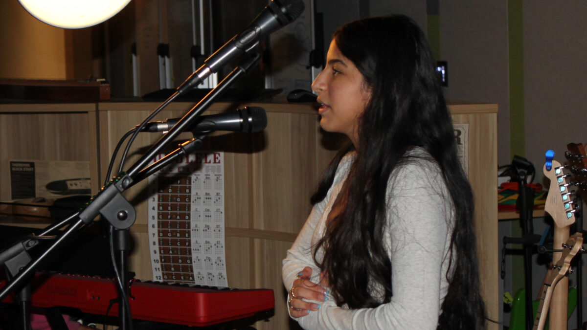 Mahika Poetry A teen standing and speaking in front of a microphone