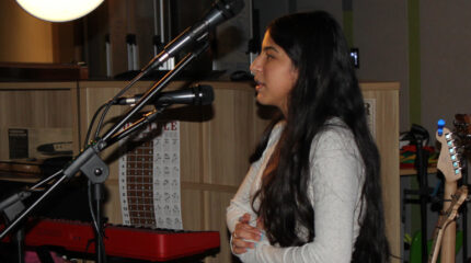 A teen standing and speaking in front of a microphone