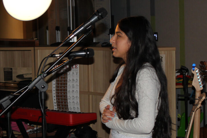 A teen standing and speaking in front of a microphone