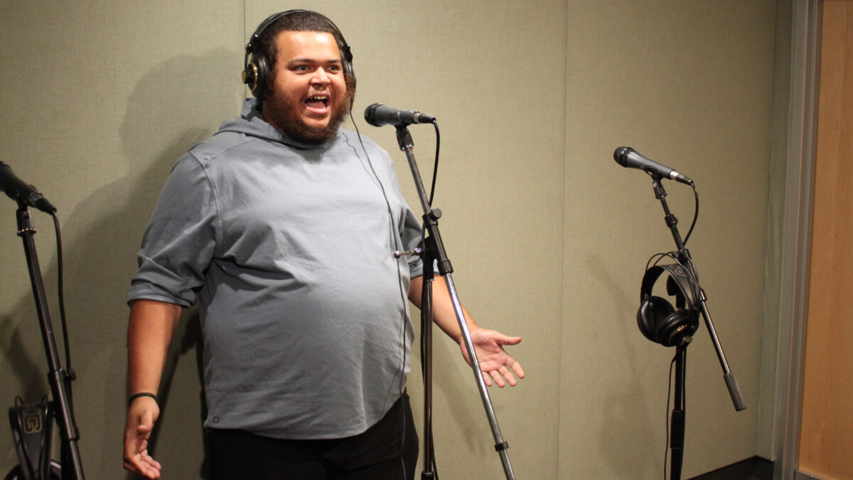 Once-On-This-Island-2 An adult singing into a microphone in a radio studio