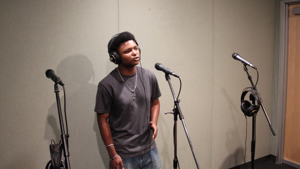 Once-On-This-Island-4 An adult singing into a microphone in a radio studio