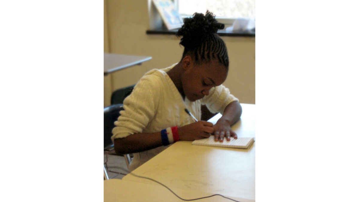 A youth writing on a notepad in a classroom