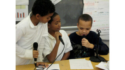 Three youth holding microphones in a classroom