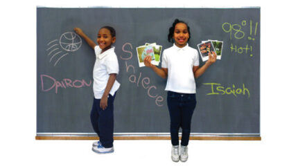 Two youth smiling and standing in front of a chalkboard