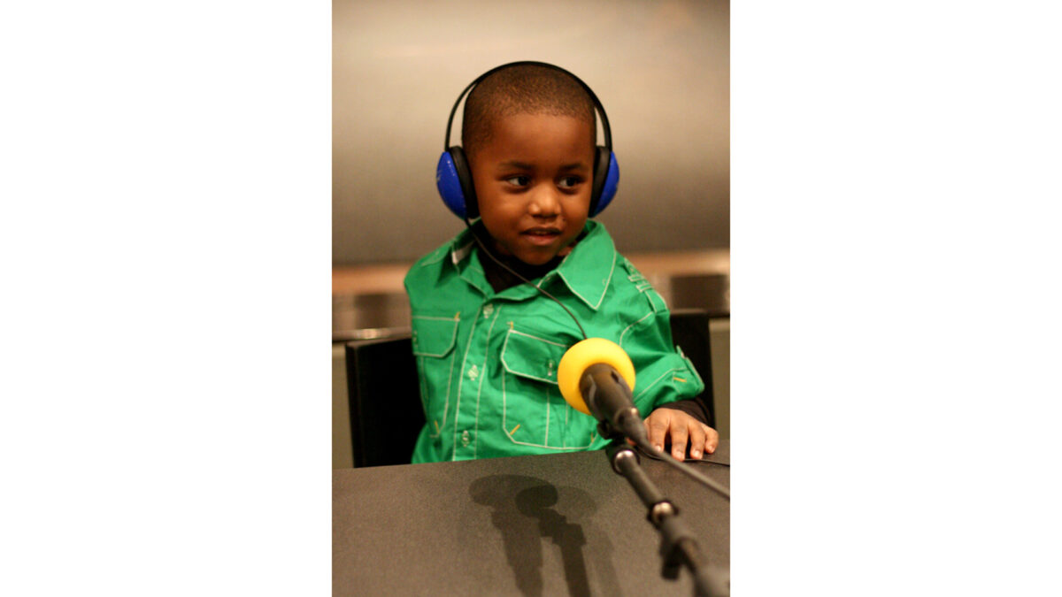 spark-animaldiscussion-01small_wp A youth wearing headphones sitting behind a microphone in a radio studio