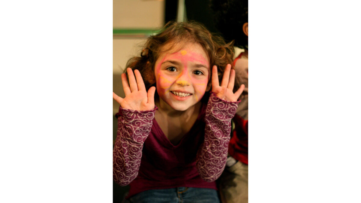 spark-animals-callasmall_wp A youth wearing face paint smiling at the camera while holding their hands up