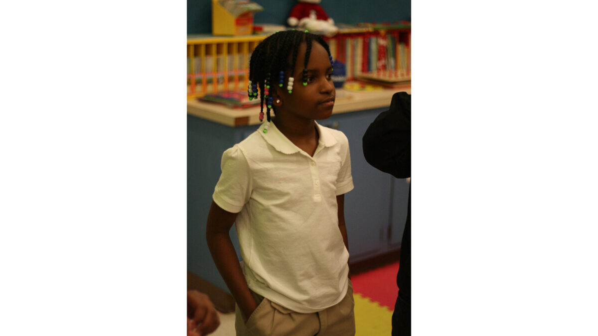 A youth with their hands in their pockets standing in a classroom