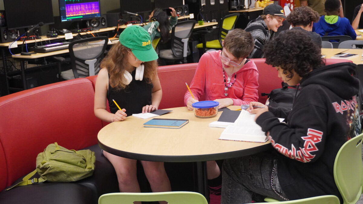 Rhyme and Reason-7 three teens write at a table together.