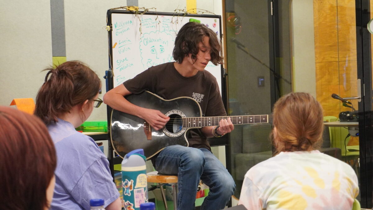 Rhyme and Reason-10 a teen plays an acoustic guitar while others listen