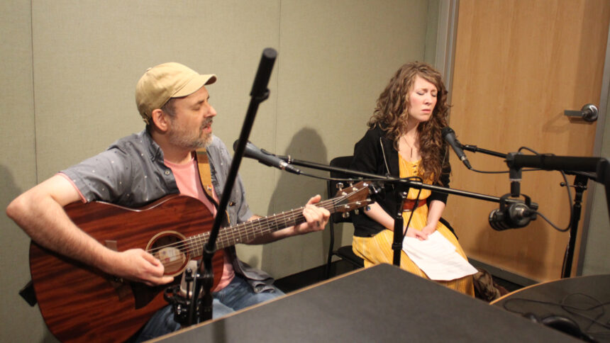An adult playing acoustic guitar and singing into a guitar and an adult singing into a microphone in a radio studio