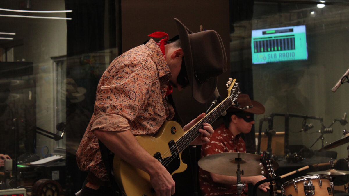 Gallop-Gallop-Gallop_3 An adult playing an electric guitar and an adult playing a drum set