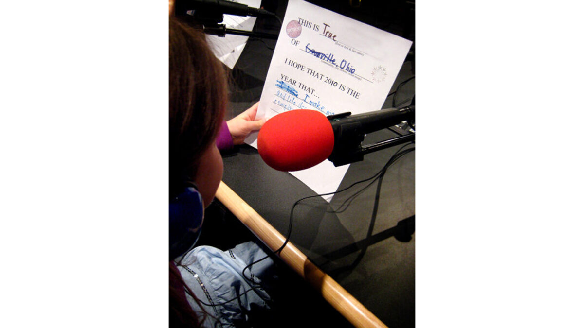 girl_wp A youth wearing headphones sitting behind a microphone looking at a piece of paper in a radio studio