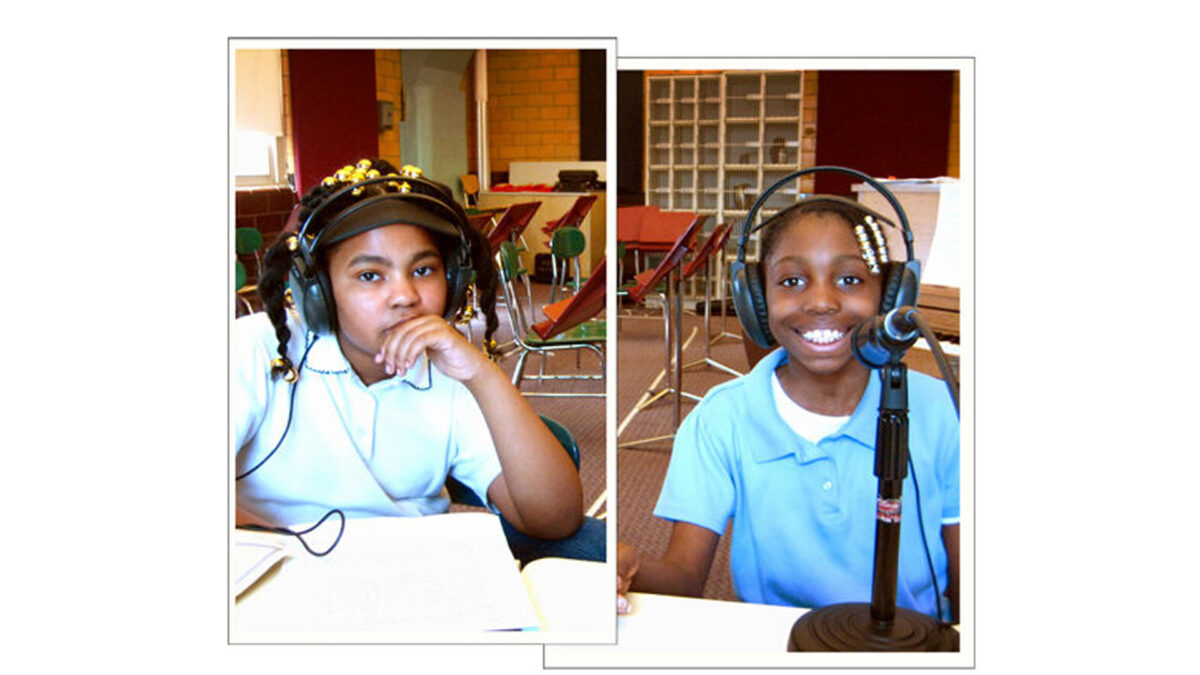 Two youth wearing headphones looking at the camera in a classroom